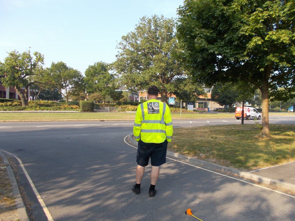 A photograph of Mark from behind. He is standing looking at a junction and he is wearing a City Infinity hi-viz.